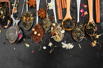 Tea in spoon on rustic black background.