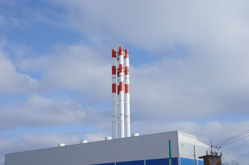 Factory pipes on a background of blue sky with clouds.