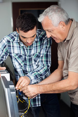 Tutor And Senior Man Fixing Computer In Class