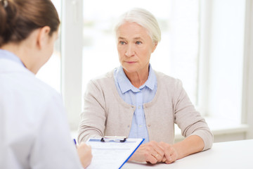 Obraz premium doctor with clipboard and senior woman at hospital