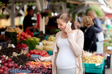 pregnant woman calling on smartphone at market