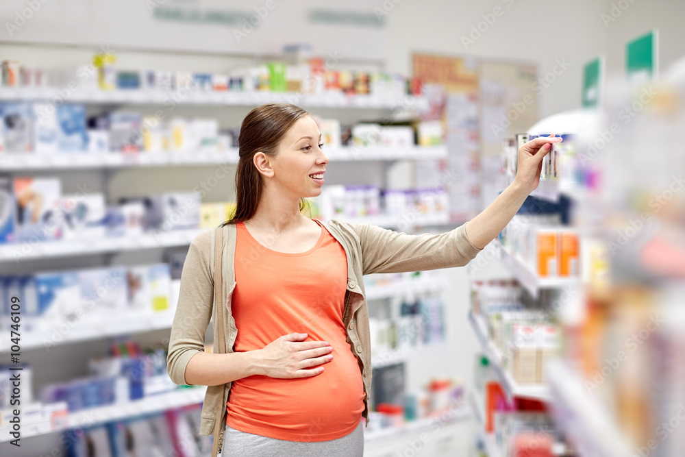 Wall mural happy pregnant woman choosing medicine at pharmacy