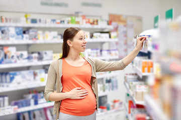 happy pregnant woman choosing medicine at pharmacy