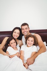 Fototapeta premium Happy family lying on bed against wall at home