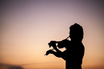 The silhouette girl playing the violin in the sunset