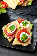 Delicious sandwich with prosciutto ham, cheese, tomato and egg