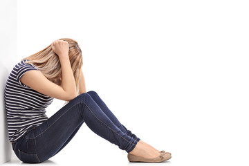 Depressed blond woman sitting on floor - Powered by Adobe