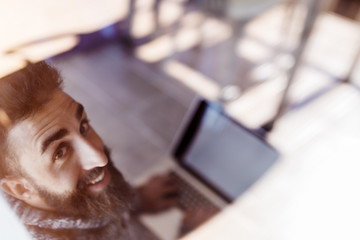 Happy hipster man working with laptop, on the other side of the