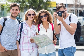 Hip friends holding map and taking picture at the camera