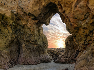 Ghost - The sea sculpted a natural arch in the shape of a ghost. The sunset spills through the archway off the Pacific Ocean coastline in Laguna Beach, California.