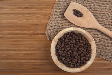 Coffee beans in bowl on wooden background