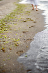 The girl in a white dress running down the beach, leaving footprints in the sand