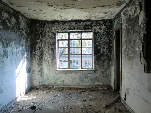 Depressing abandoned room with centered window - landscape color photo