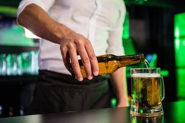 Mid section of bartender pouring beer in a glass - Powered by Adobe