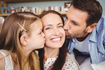 Close-up of father and daughter kissing mother