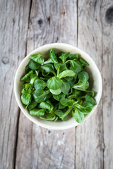 Insalata Valeriana in una coppa su un tavolo di legno chiaro