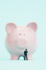 Miniature businessman and piggy bank.