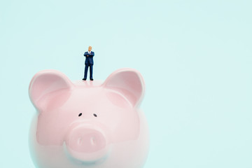 Miniature businessman and piggy bank.