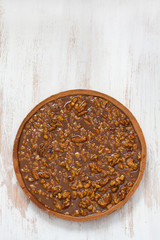 nuts tart with caramel on white wooden background