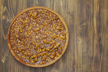 nuts tart with caramel on brown wooden background
