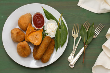 portuguese appetizers with sauces on white plate on green background