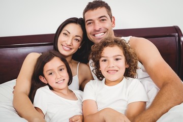 Cheerful family lying on bed against wall at home