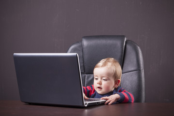 Little boy playing with a laptop against grunge background