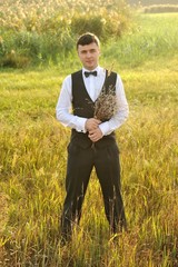 Groom in a vested suit posing in the field
