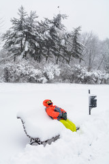 Little boy laying on bench with snow. Vertical view with child i