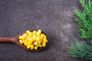  Green branch  and wooden spoon full of sweet corn on gray background  © kemilii