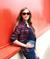 Pretty smiling woman in sunglasses over red background