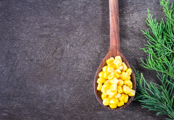  Green branch  and wooden spoon full of sweet corn on gray background  © kemilii