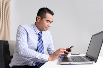 Asian business man using mobile smart phone in his office