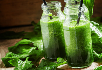 Healthy spinach smoothies, detox drink in glass bottles on the o