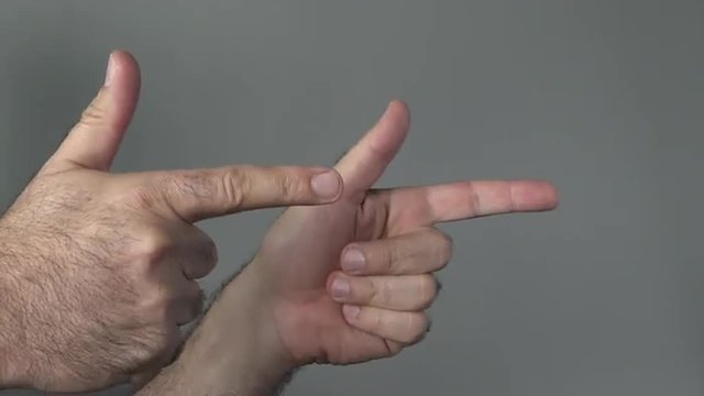 Man show guns with his fingers on a grey background. Concepts and ideas with copy space