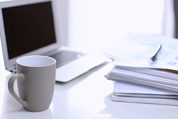 .Office workplace with a laptop and financial documents on the light reflecting table