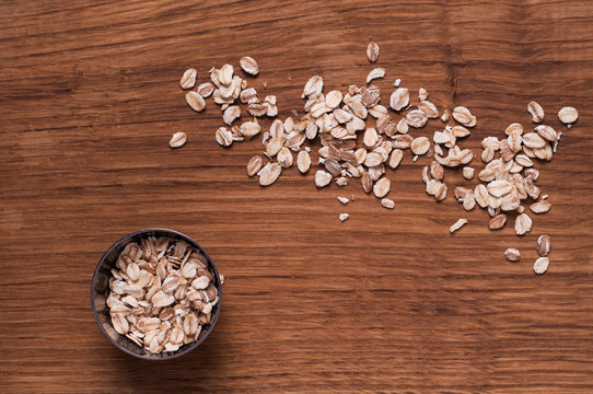 Oat flakes in metal bowl on brown wooden table