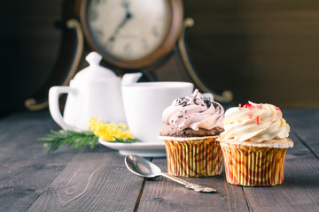 cupcakes and cup of tra on dark wooden background