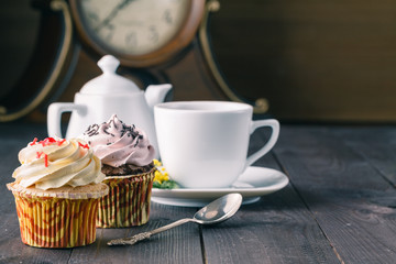 cupcakes and cup of tra on dark wooden background