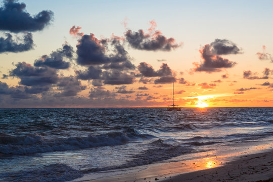 Fluffy dark clouds floating over turbulent ocean waters on sandy beach shore