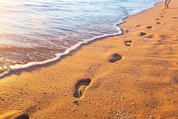 Obraz na płótnie Canvas beach, wave and footprints at sunset time