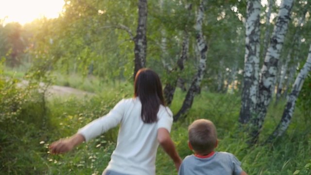 Mom and her son run in birch forest during sunset in slowmotion. 1920x1080. hd