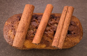Cinnamon sticks and cake with jam on light brown background