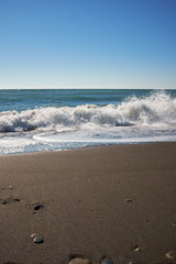 Waves wash over dark sand on the beach