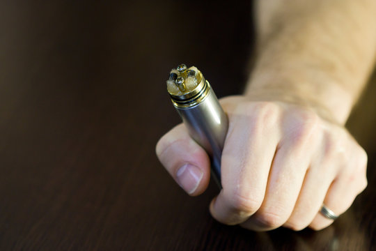 Advanced personal vaporizer or e-cigarette in his hand