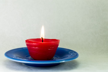 Obraz na płótnie Canvas candela rossa accesa su piattino blu