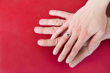 Wedding couple hands with wedding rings on red background