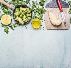 raw broccoli in a pan with herbs, lemon, celery root on a cutting board with a knife border ,place for text on wooden rustic background top view close up
