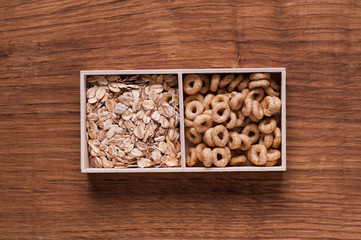 cereals and oat flakes in wooden box on brown wooden table - top