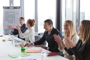 Business people clapping hands during the meeting in modern office.